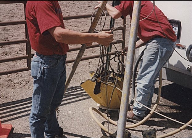 Two workers lifting a loaded Debris Catcher out of a manhole